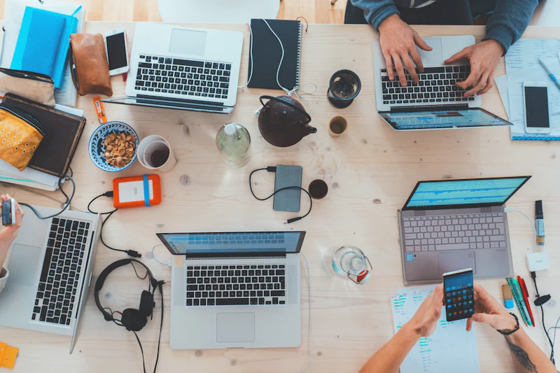 A team working together around a table of laptops, seen from above